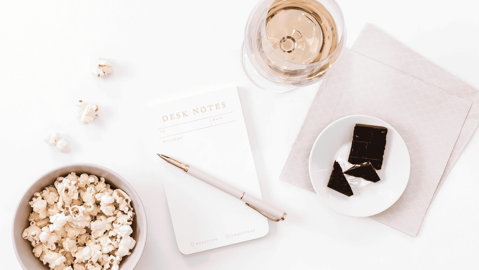 A peaceful workspace with popcorn, a pen, a notepad, and chocolates for relaxation.