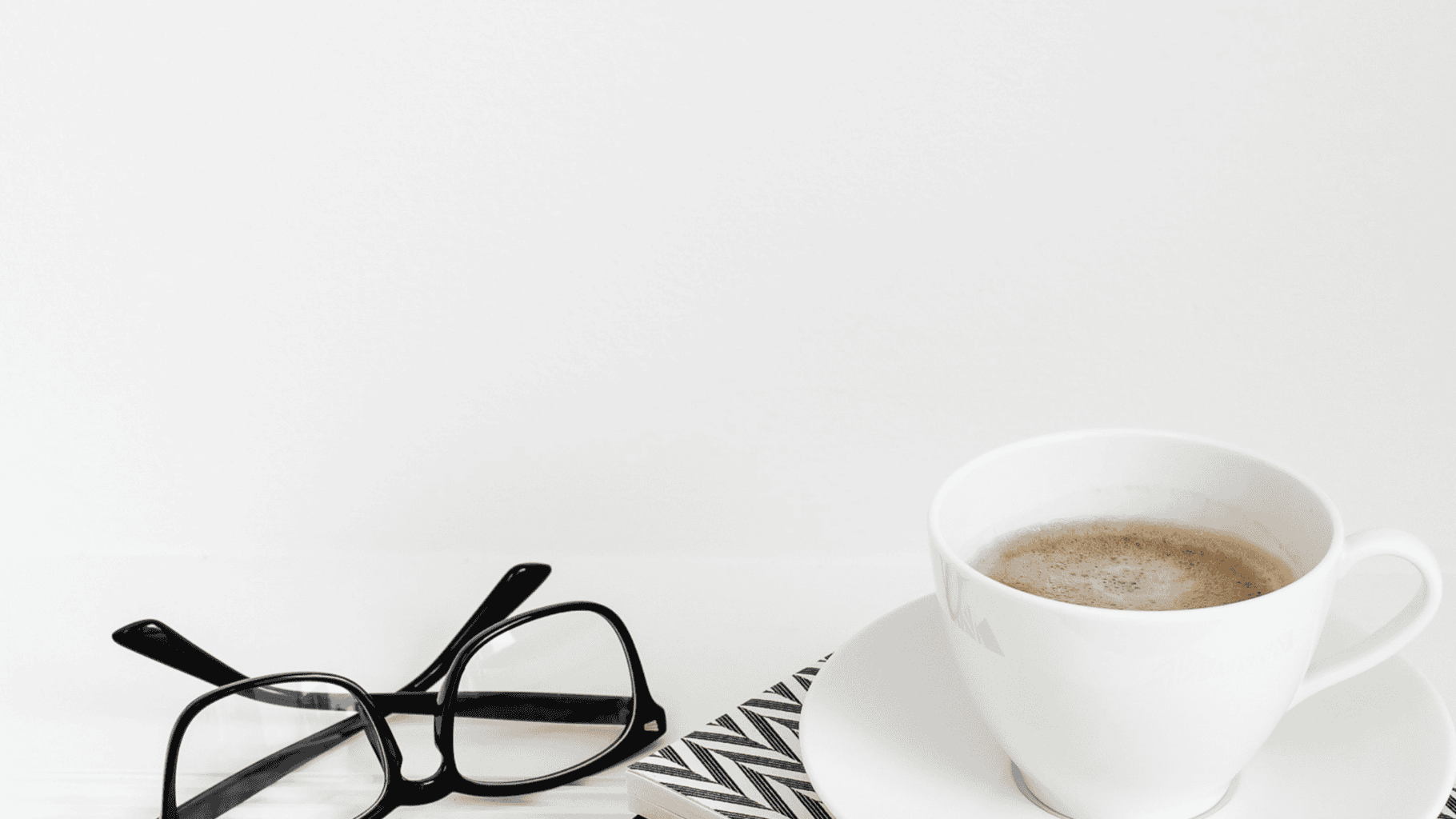 Coffee and glasses on a white surface, symbolising reflection and contemplation.