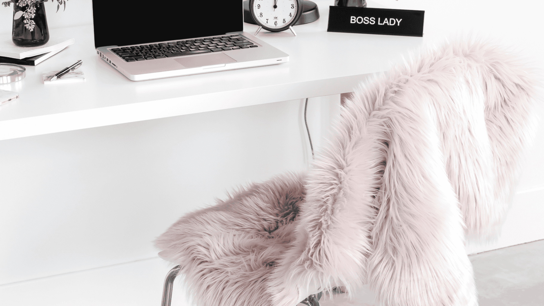 Cozy workspace with a fluffy pink chair and a clean white desk.