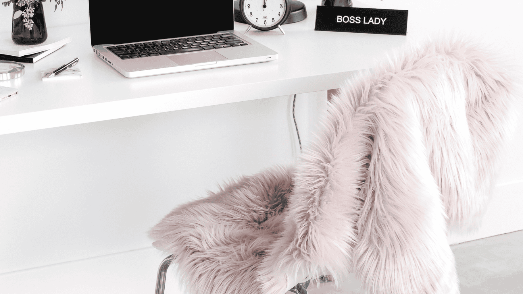 Cozy home office with a fluffy pink chair and minimalist desk.