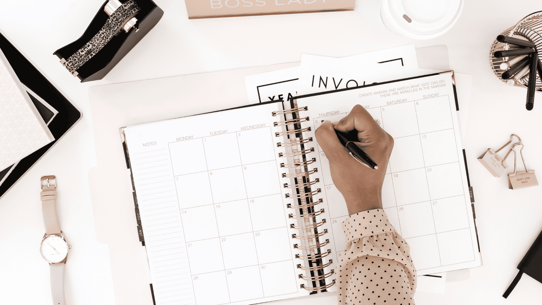 Person writing in a planner with marriage notes and stationery around.