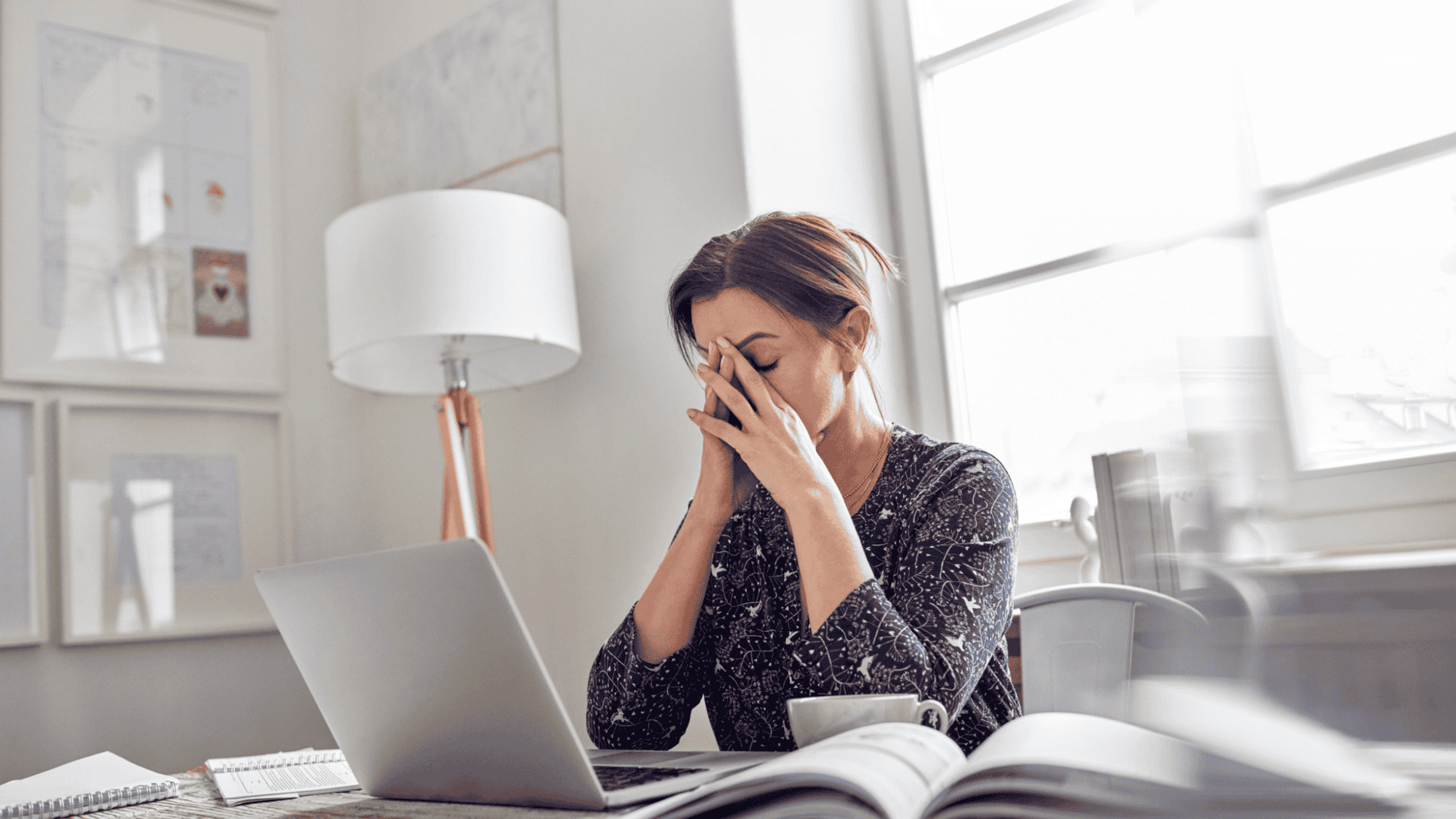 Stressed woman feeling overwhelmed while working on her laptop at home.